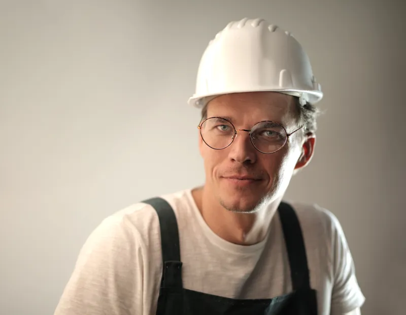 Porträt eines Handwerkers mit weißem Schutzhelm und Brille